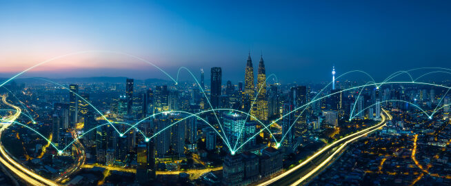 City at night with rays of light representing network connections flashing over the buildings